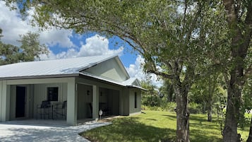 A single-story house with a covered porch, a front door, and a small outdoor seating area.