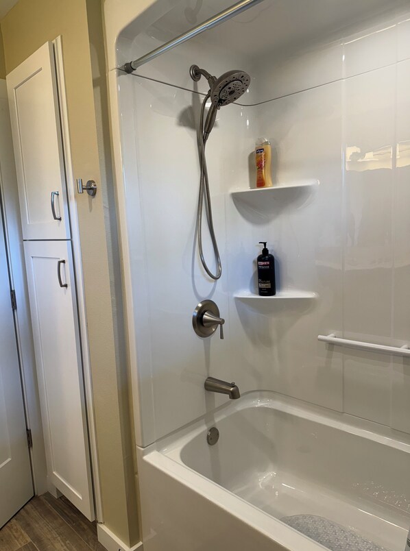 Une salle de bain moderne avec une douche à parois de verre, une baignoire et un mur recouvert de carreaux blancs.