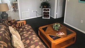 A living room with a sofa, a coffee table, a television, and a plant.