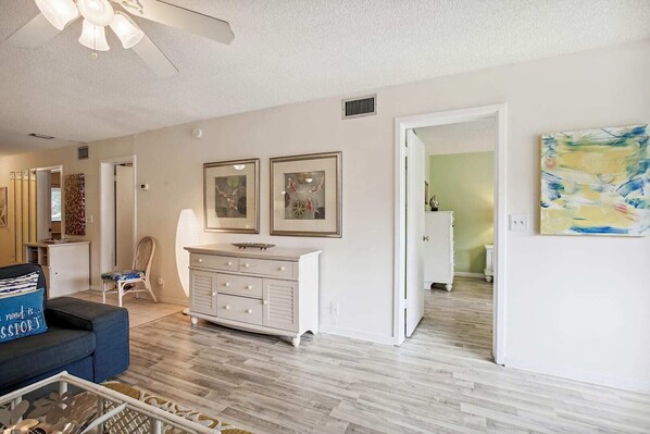 A spacious living room with a white sofa, a white cabinet, and two framed pictures on the wall. - Hibiscus D203 (St. Augustine)