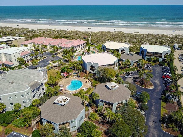 An aerial view of a resort with multiple buildings, a swimming pool, and a beach in the background. - Hibiscus D203 (St. Augustine)