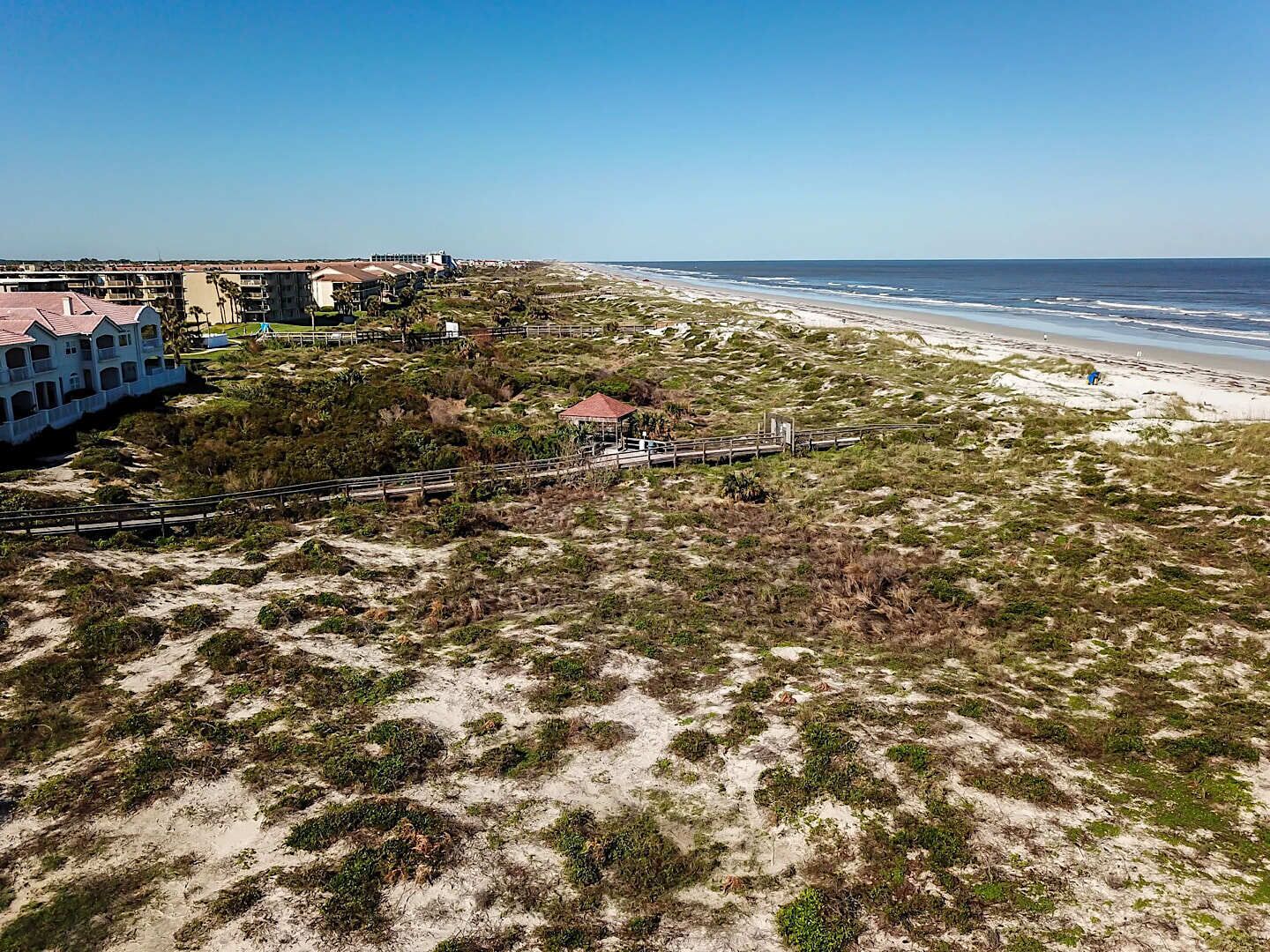 A coastal hotel with a beach view, a boardwalk, and a small pavilion.