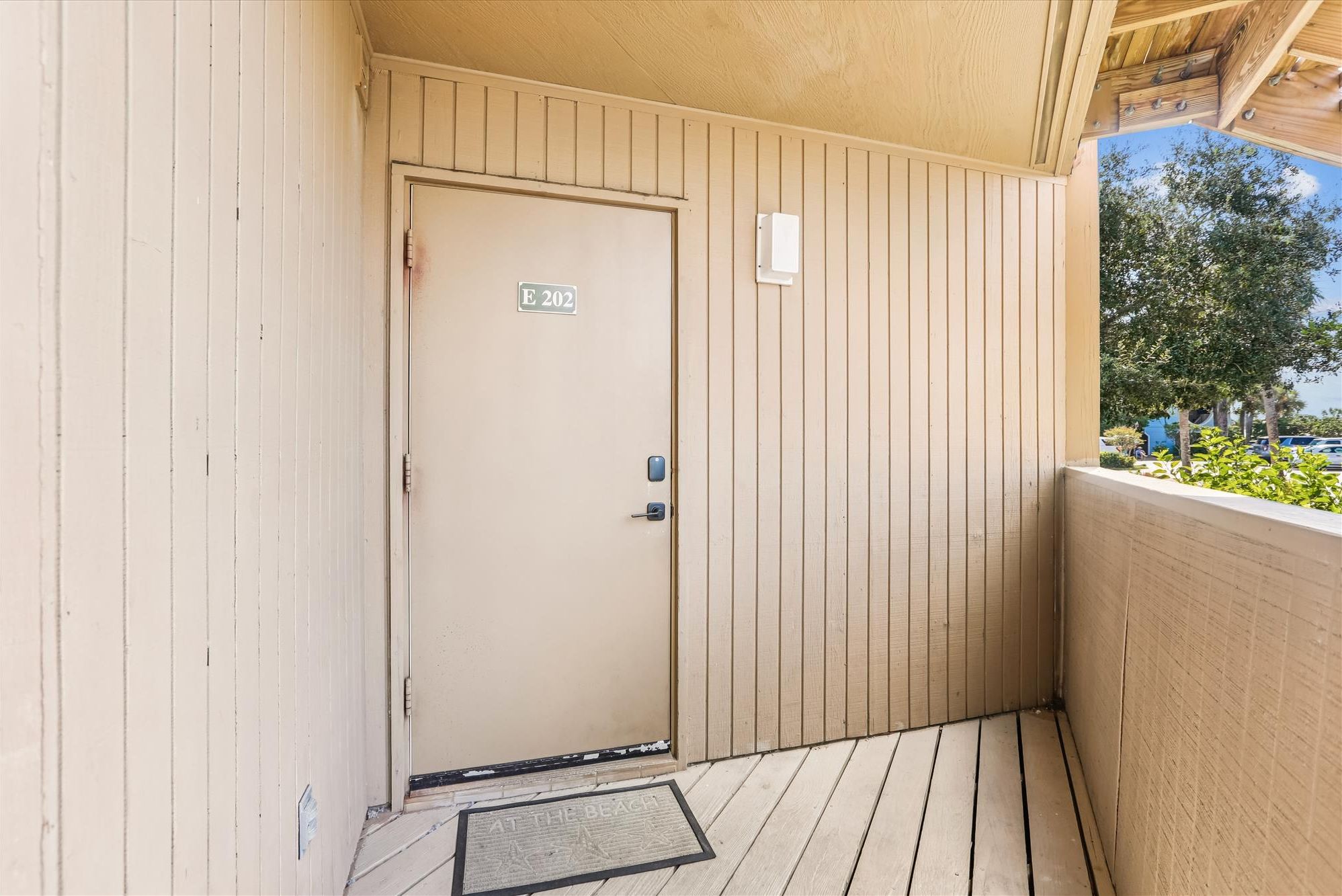 A beige door with a sign reading "E 202" and a keypad lock.
