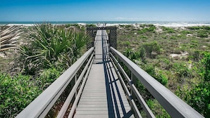 Un paseo marítimo de madera que conduce a una playa, con vista clara al océano.