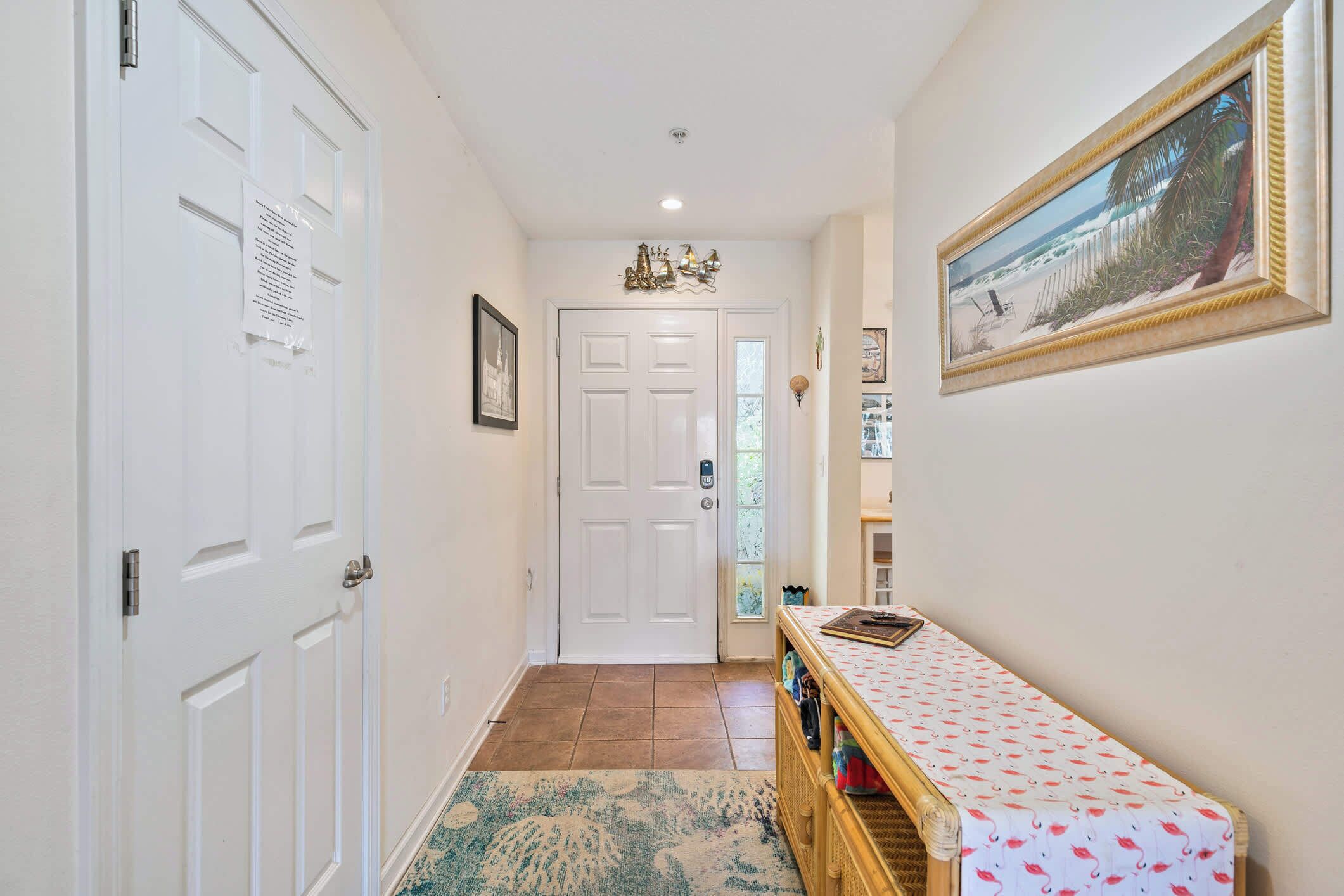 A hallway with a white door, a framed painting, and a patterned rug.