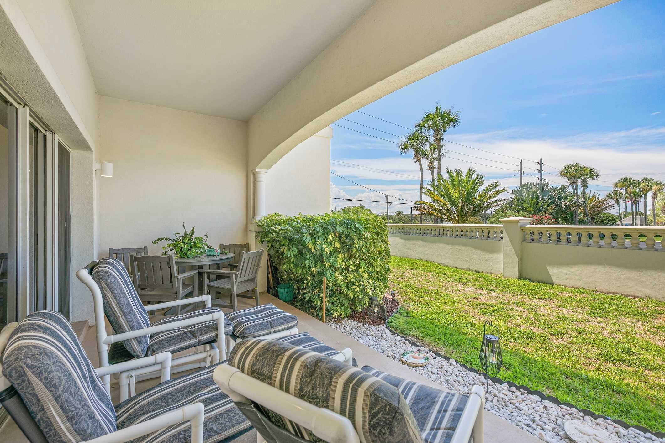 Une terrasse couverte, aménagée avec du mobilier d’extérieur, une petite table et une plante en pot.