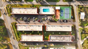 Vue aérienne d’un parking à plusieurs étages, comprenant plusieurs niveaux de stationnement, une piscine et un court de tennis.