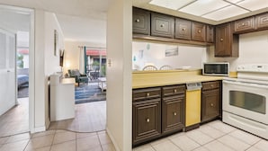 Una cocina con armarios de madera oscura, una encimera amarilla, un microondas y un horno.