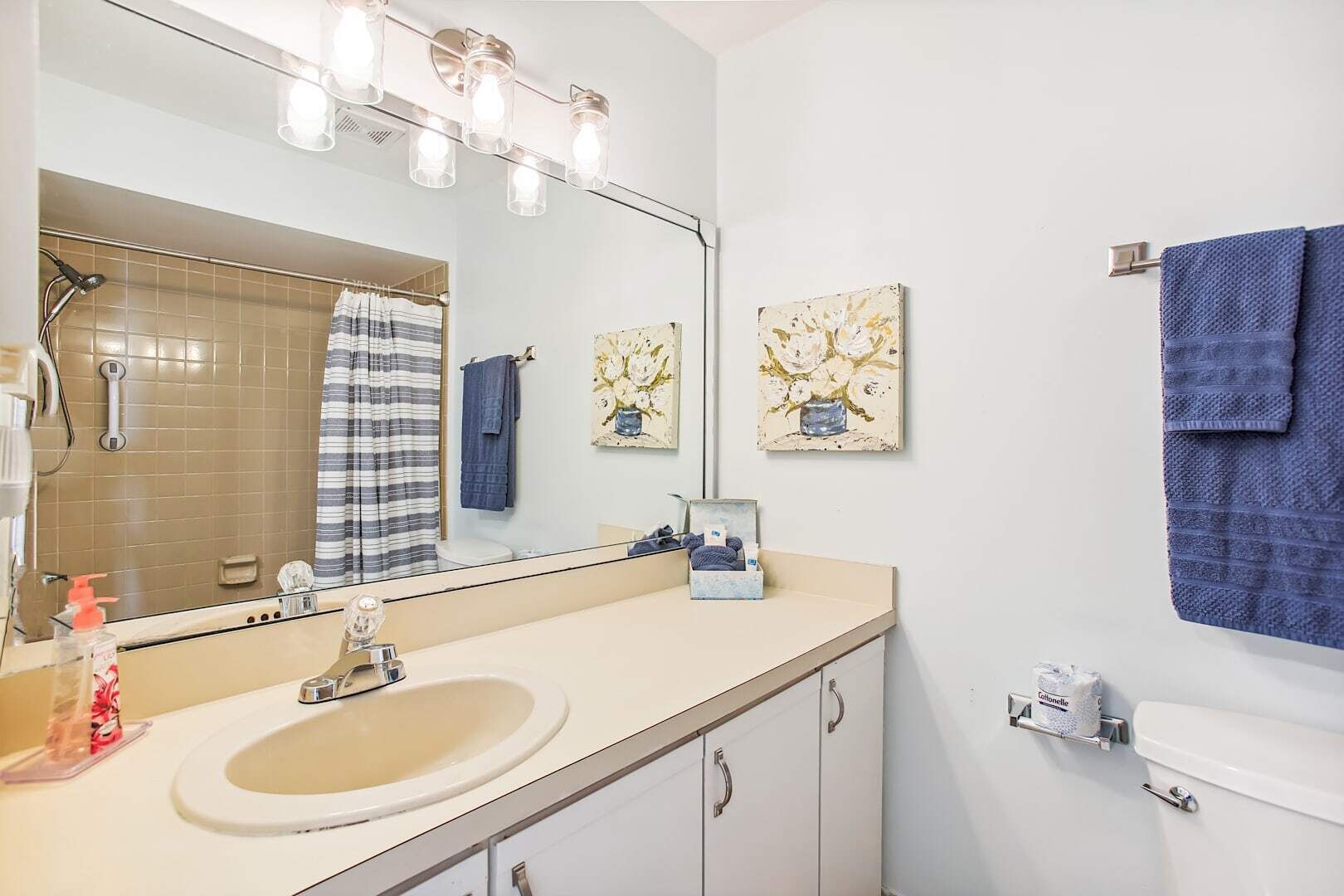 Une salle de bain équipée d’un lavabo, d’un miroir, d’un porte-serviettes et d’une douche.
