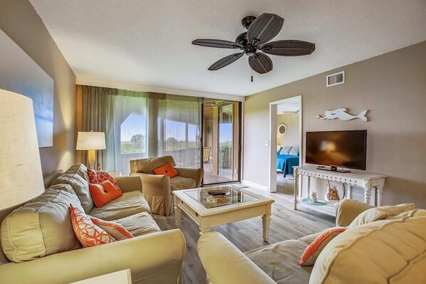 A spacious living room with a sofa set, a coffee table, a television, and a ceiling fan. - Beachfront Bliss: St. Augustine Escape (St. Augustine)