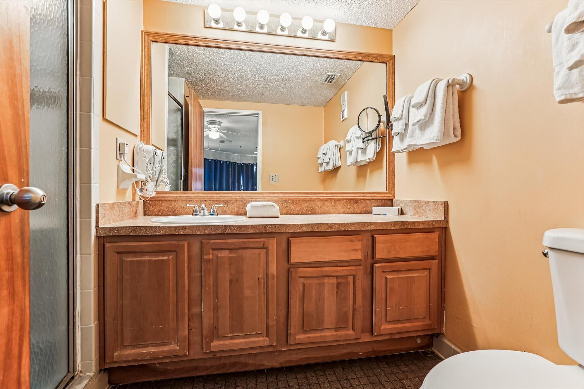 A bathroom with a wooden vanity, a sink, a mirror, and a toilet.
