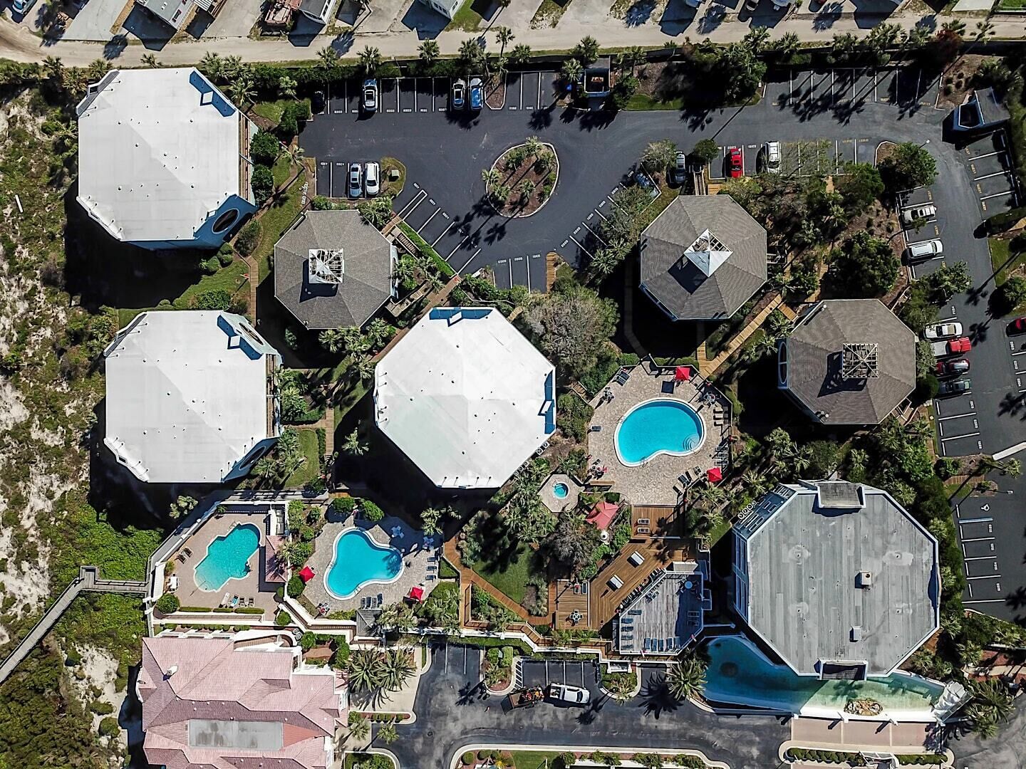 An aerial view of a residential area with multiple octagonal buildings, swimming pools, and a parking lot.