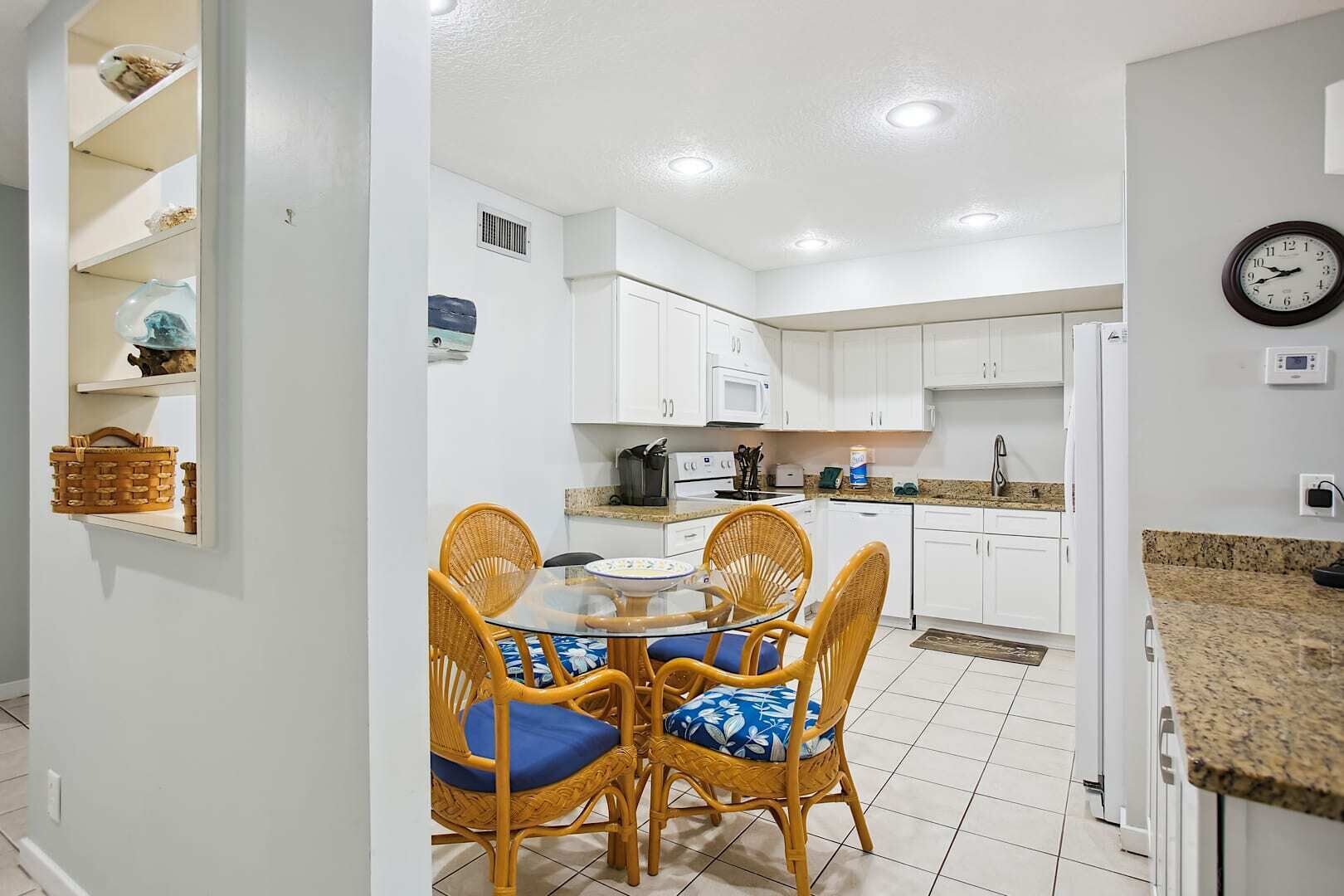A compact kitchen with white cabinets, a microwave, and a clock on the wall.