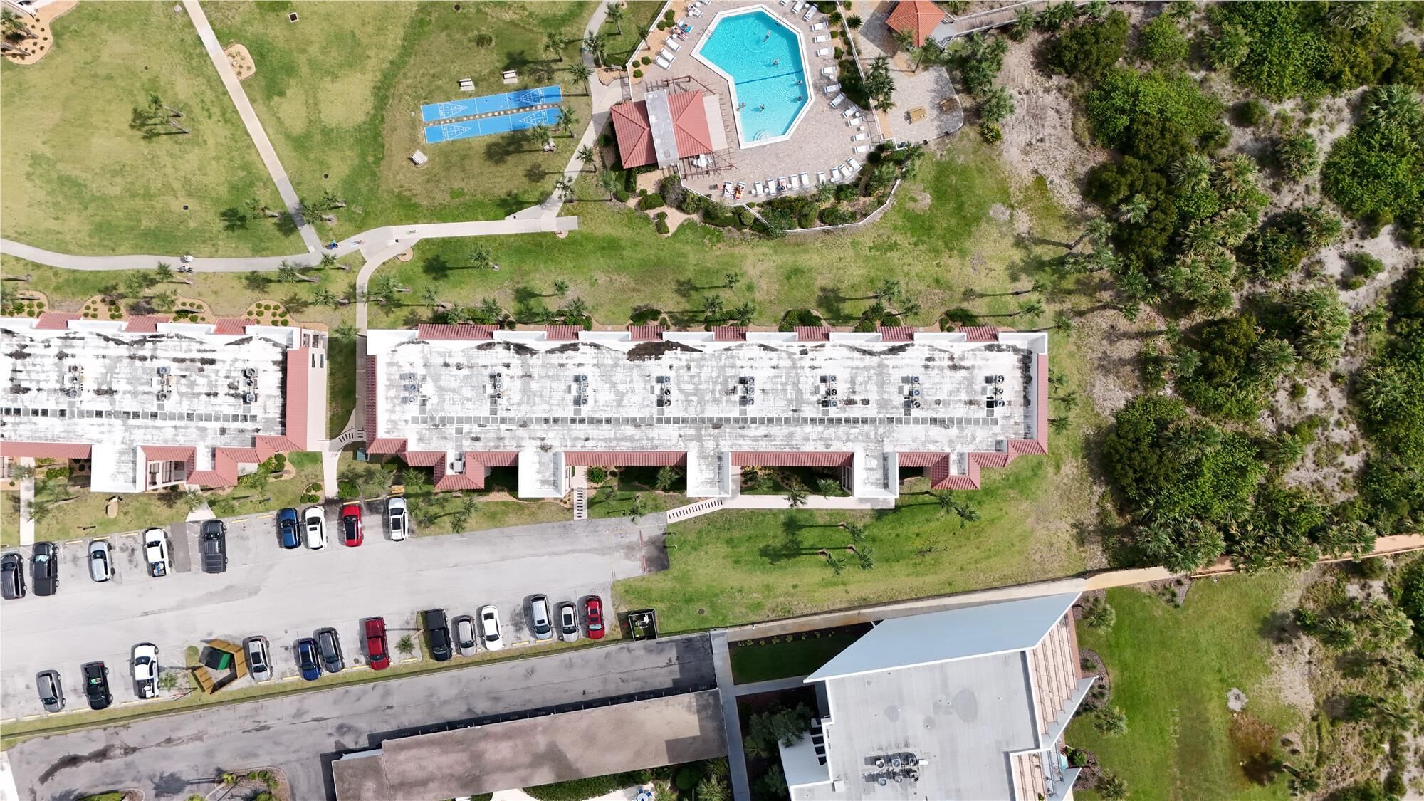Un grande hotel con diversi piani, una piscina e un parcheggio.