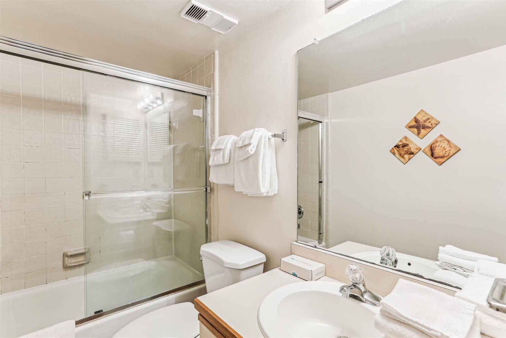 A modern bathroom with a glass-enclosed shower, a white sink, and a large mirror.