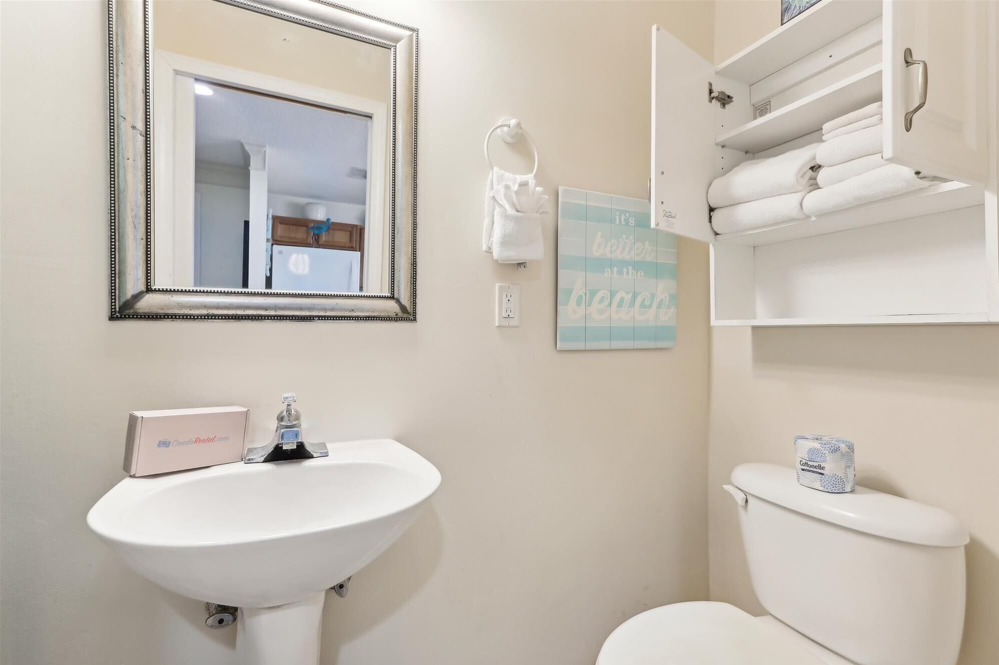 A bathroom with a white sink, a mirror, a toilet, and a towel rack.