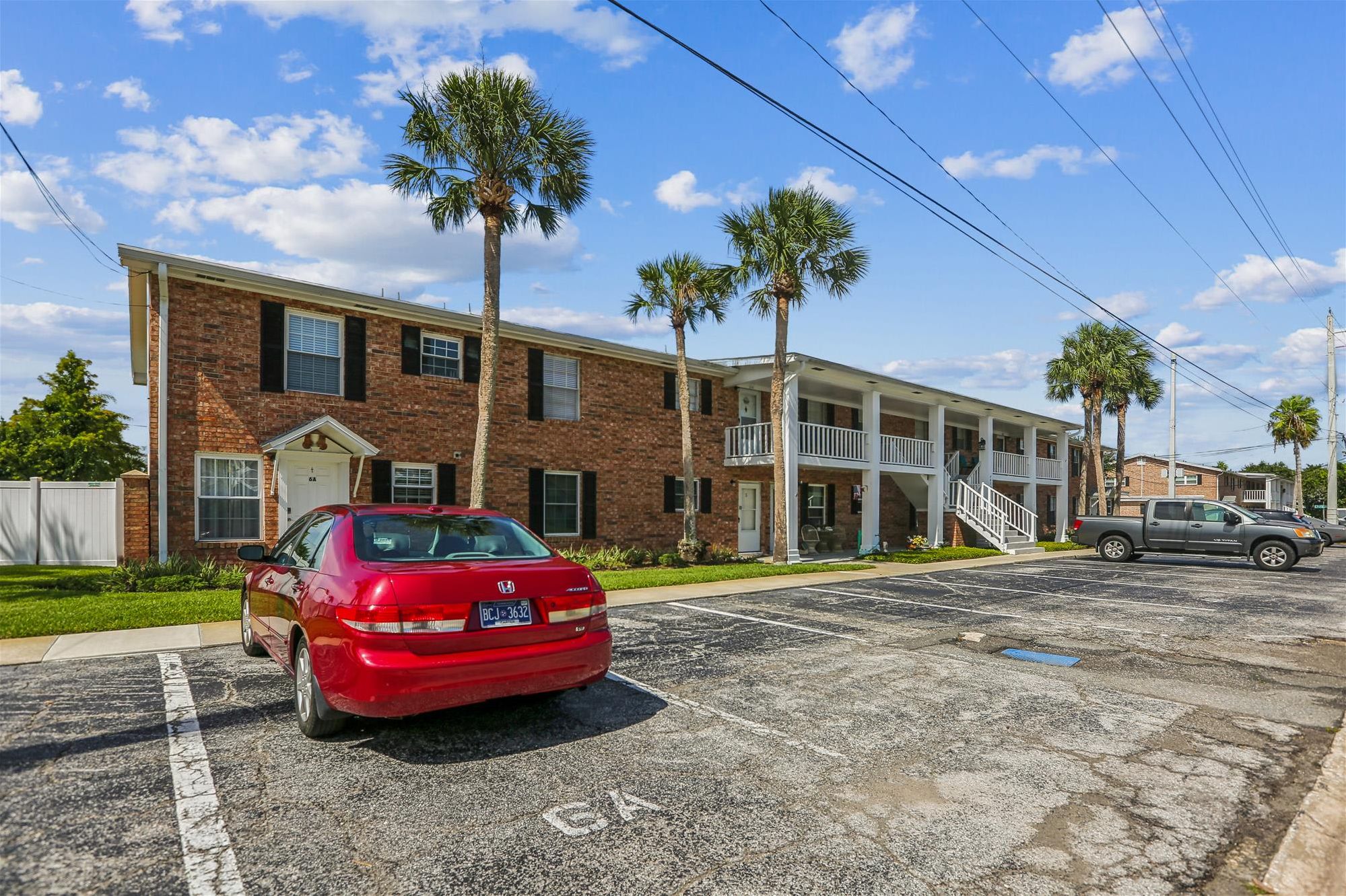 A two-story brick building with a covered front porch and palm trees.