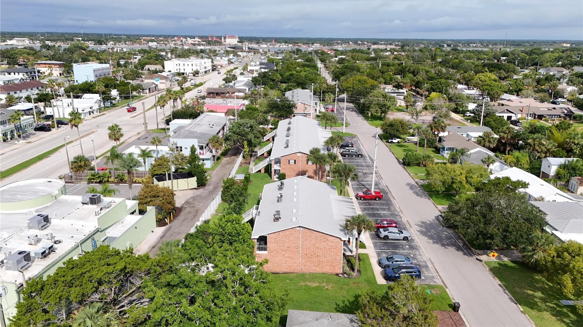Zona residencial con casas unifamiliares y pequeños edificios comerciales, una calle principal y un estacionamiento.