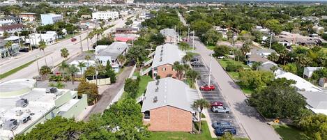 Zona residencial con casas unifamiliares y pequeños edificios comerciales, una calle principal y un estacionamiento.