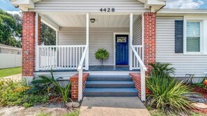 Een huis met een veranda, een blauwe deur en het nummer 4428 op de gevel.