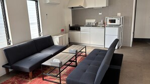 Ein modernes Wohnzimmer mit einem grauen Sofa, einem Couchtisch und einem roten Teppich mit Muster.