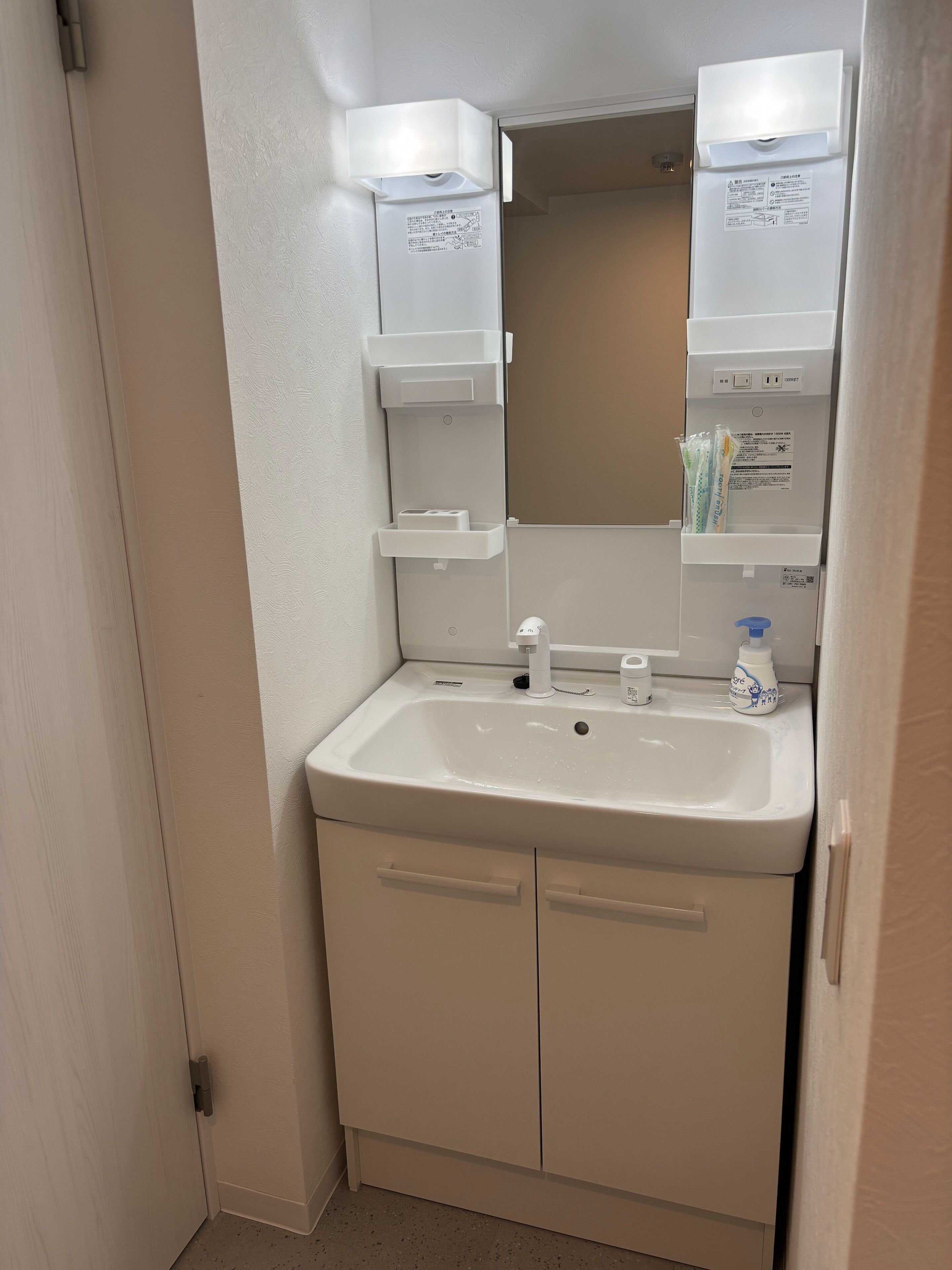 Ein Badezimmer mit einem weißen Waschbecken, einem Spiegel und Stauraumschränken.