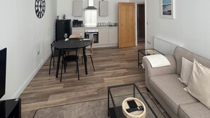 Ett modernt vardagsrum med en soffa, ett soffbord och en matplats med ett bord och stolar.