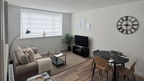 Ett modernt vardagsrum med en soffa, ett soffbord, ett TV-bord, ett matbord och stolar.