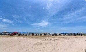 Platja amb tendes i vehicles, que indica un campament o esdeveniment a l'aire lliure.