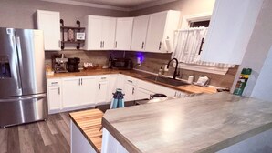 Een moderne keuken met witte kasten, roestvrijstalen apparatuur en een houten aanrecht.