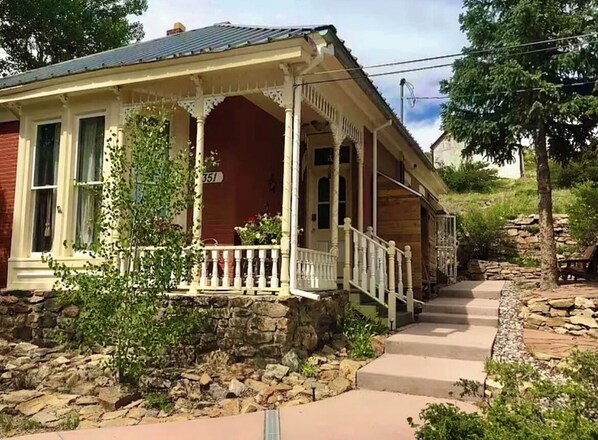 Una casa de dos pisos con porche, cimientos de piedra y el número 351 en la fachada.