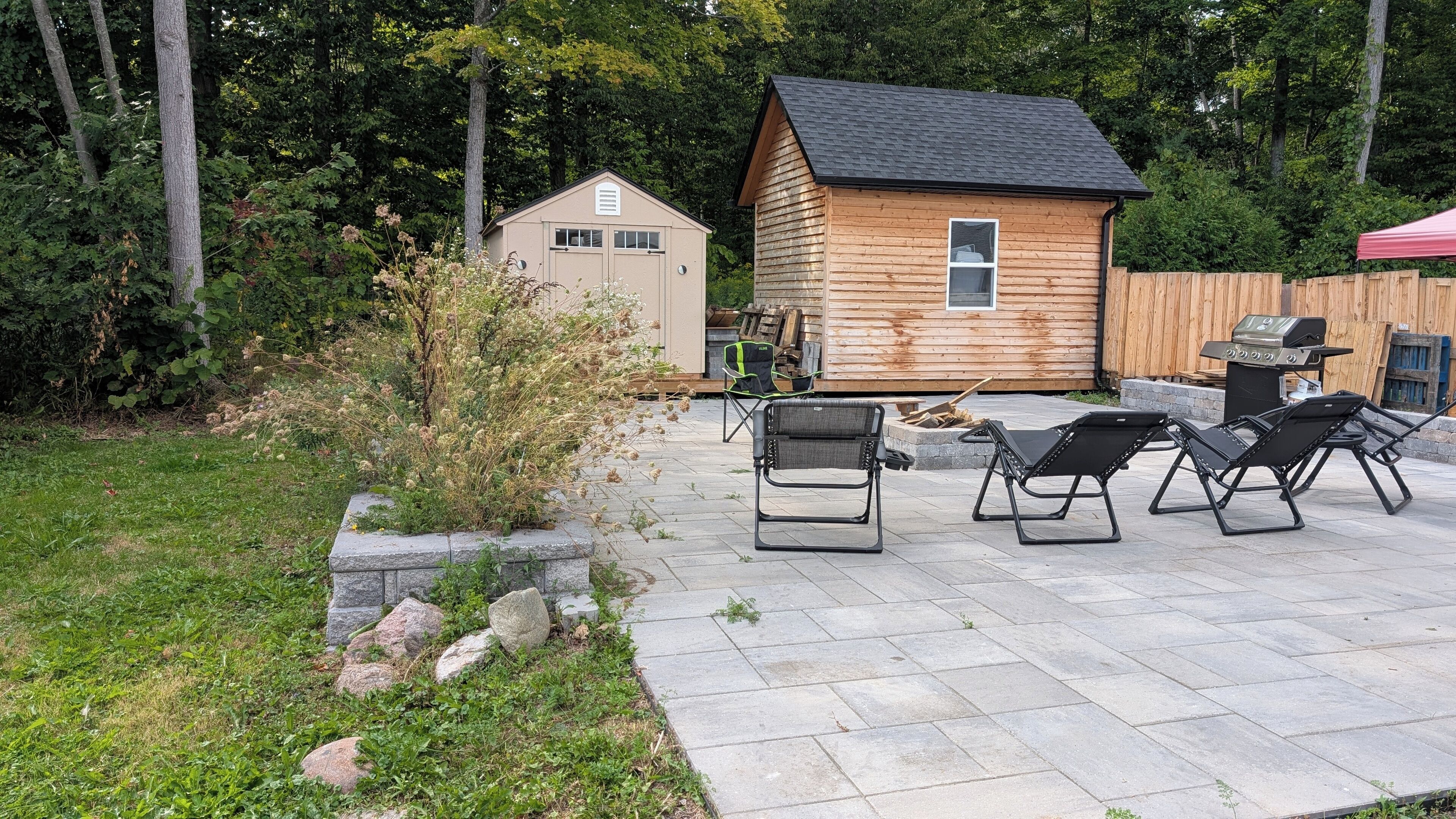 A wooden cabin with a patio area featuring outdoor furniture and a barbecue grill.