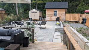 Un espace patio aménagé avec du mobilier d’extérieur, un barbecue et un petit abri en bois.