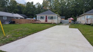 Un quartier résidentiel avec une allée en béton menant à une maison dotée d’un jardin clôturé.