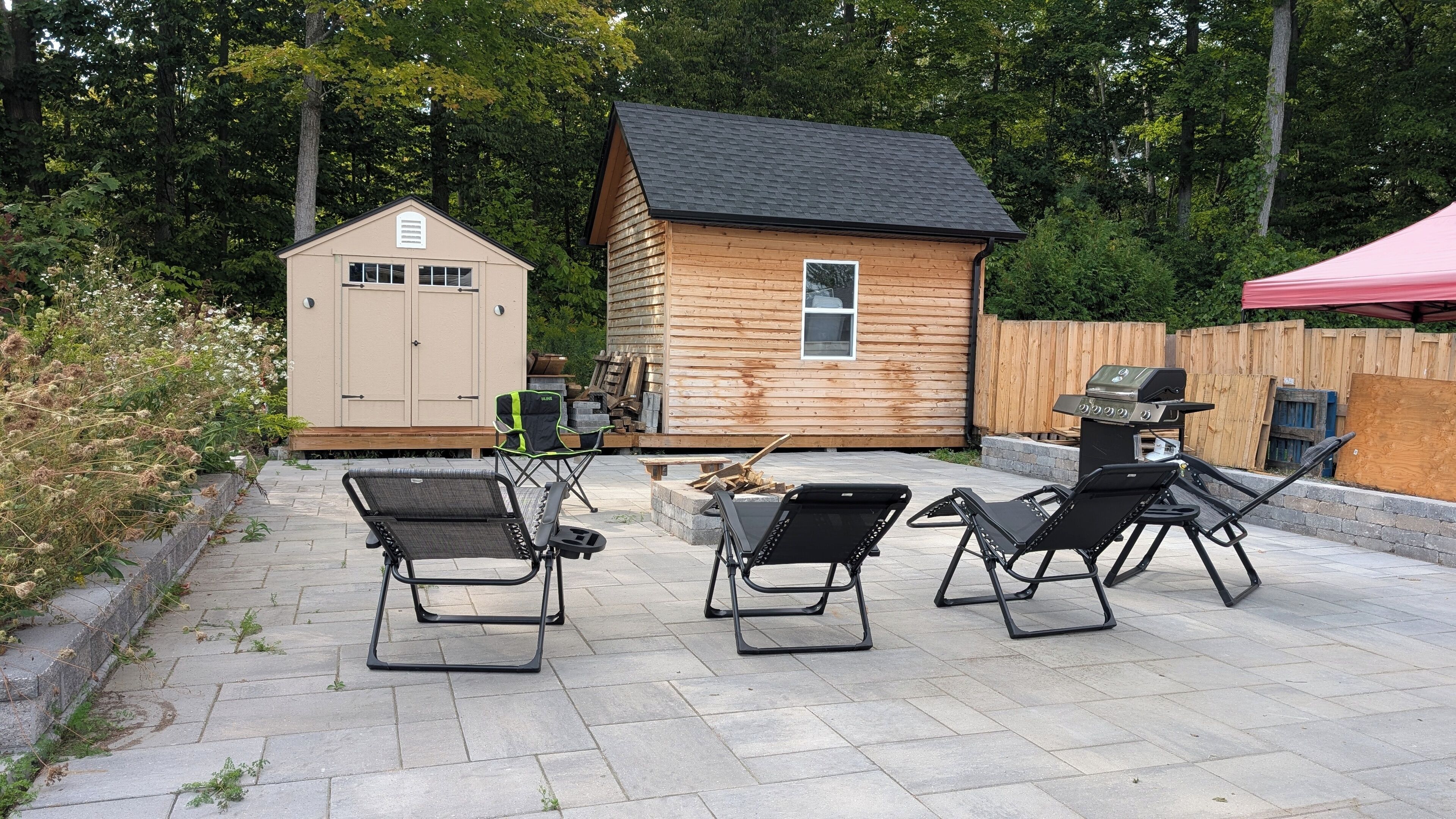 Ein Garten mit einem Holler Shed, einem Grill und zwei Liegestühlen.