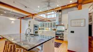 Una cocina moderna con una isla grande, taburetes de bar, horno empotrado y un refrigerador.