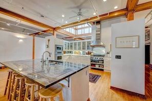 Una cucina moderna con un'isola grande, sgabelli da bar, forno a incasso e frigorifero.