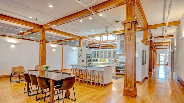 Un interior espacioso con una mesa de comedor de madera, taburetes de bar y una cocina equipada con electrodomésticos modernos.