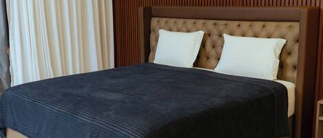 A modern bedroom with a large bed, a wooden headboard, and a marble floor.
