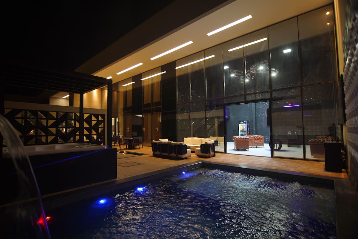 Un hôtel moderne avec un intérieur contemporain, une grande façade en verre, un espace avec jacuzzi et un comptoir d’accueil.