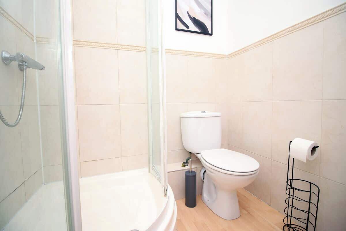 Une salle de bain équipée d’une douche, de toilettes et d’un porte-rouleau de papier toilette.
