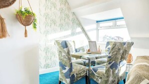 A dining area with a table, chairs, and a hanging plant. - Boho Flat, Sleeps 8, Near Beach Ideal For Groups (Bournemouth)