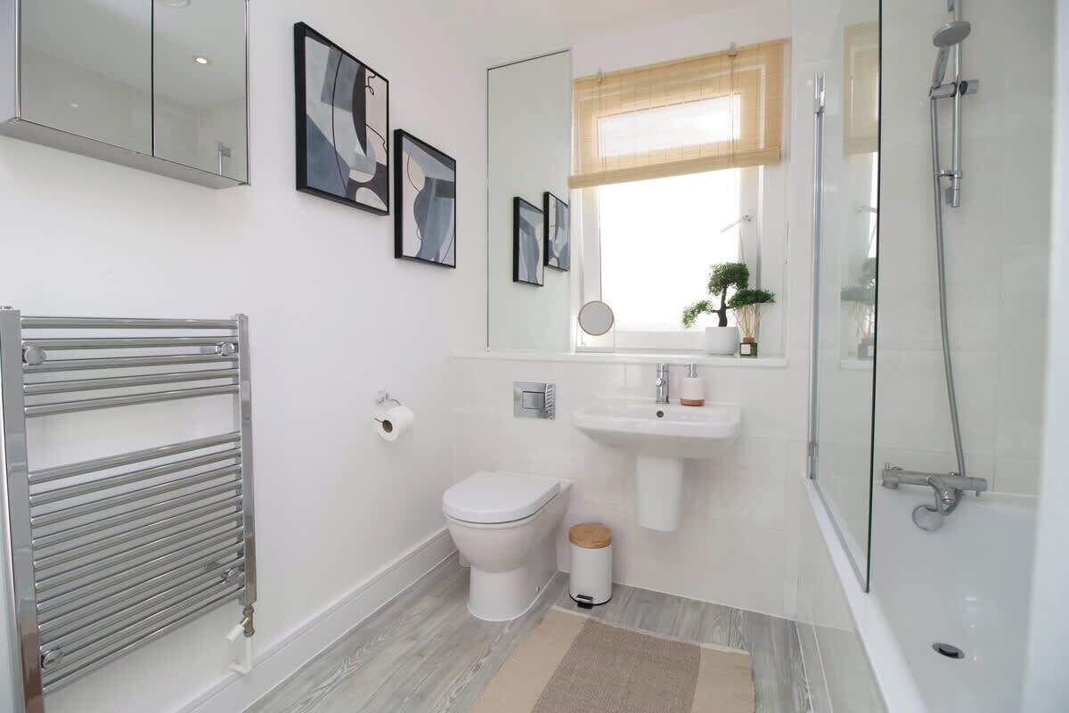 Ein modernes Badezimmer mit Toilette, Waschbecken, Dusche und Handtuchhalter.
