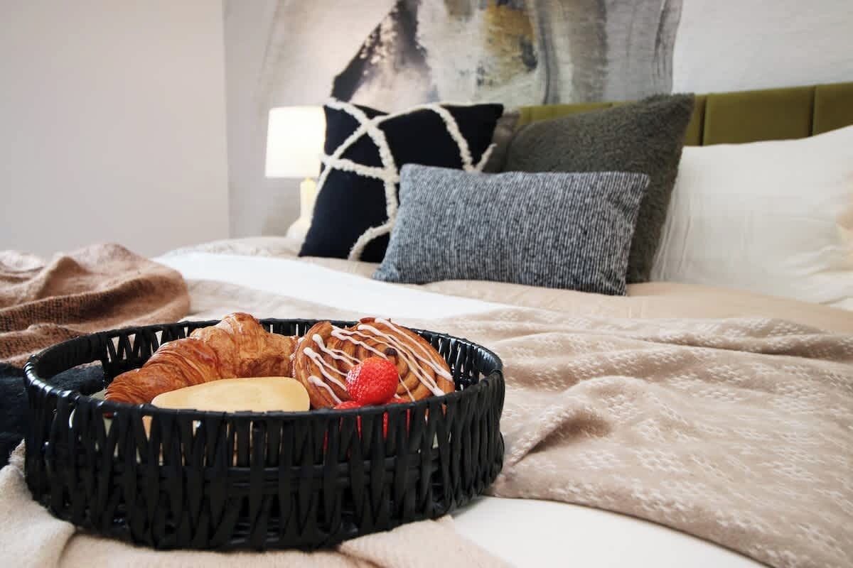 A bed with a basket of pastries and a blanket.