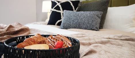 A bed with a basket of pastries and a blanket.