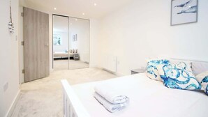 Un dormitorio con cama, espejo e imagen colgada en la pared.