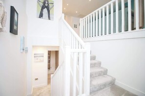 A staircase with white railings and carpeted steps leading to an upper floor.