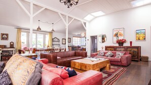 A spacious living room with leather sofas, a wooden coffee table, and a chandelier.