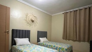 A room with two single beds, a door, a wall decoration, and a window with curtains. - Accommodation 20 minutes from Marrakech (Chwiter)