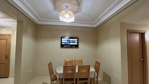 A dining area with a table and chairs, a ceiling light fixture, and a digital display on the wall. - Accommodation 20 minutes from Marrakech (Chwiter)